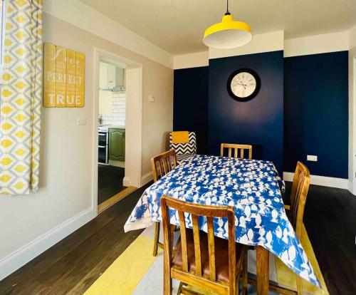 a dining room with a table and a clock on the wall at NEW homely countryside escape in Manningtree