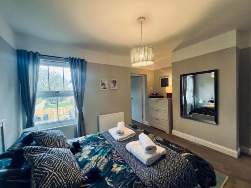 a bedroom with a bed with towels and a mirror at NEW homely countryside escape in Manningtree