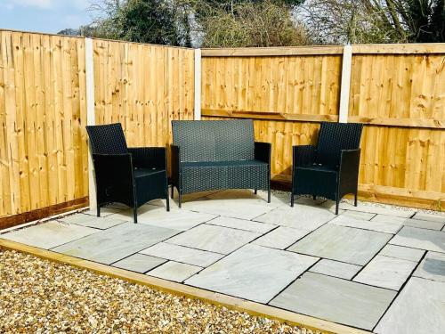 three chairs sitting on a patio in front of a fence at NEW homely countryside escape in Manningtree