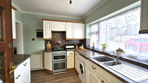 a kitchen with white cabinets and a sink and a window at Beckside - Peaceful Garden House, Dog Friendly in York