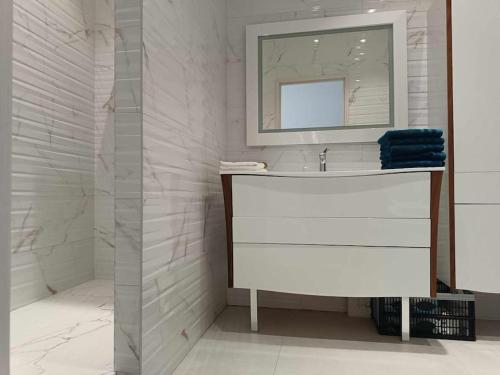 une salle de bain blanche avec un lavabo et un miroir dans l'établissement Villa moderne climatisée, piscine billard jacuzzi, à Avignon