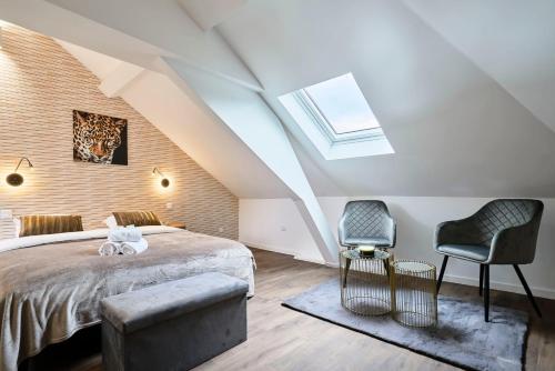- une chambre mansardée avec un lit et deux chaises dans l'établissement NG Prestige - TV - Netflix - WIFI, à Tourcoing