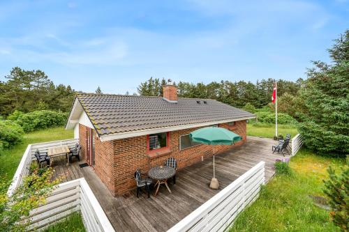 a house with a deck with a green umbrella at Cozy Holiday Home, Located In The Peaceful Area Of Klegod - 1038 in Ringkøbing