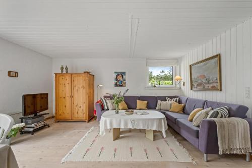 a living room with a purple couch and a table at Cozy Holiday Home, Located In The Peaceful Area Of Klegod - 1038 in Ringkøbing