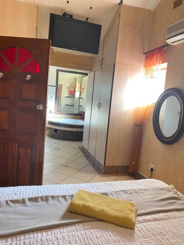 a bedroom with a bed with a mirror and a door at The Red room in Phalaborwa