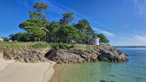 une plage avec une maison au sommet d'une falaise dans l'établissement Kerambigorn, à Fouesnant