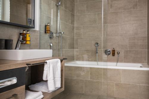 a bathroom with a tub and a sink and a shower at 24 by AvenidA - Mountain Hotel in Kaprun