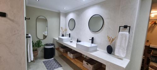 a bathroom with two sinks and mirrors on the wall at Buffalo Thorn Villa next to Kruger National Park in Marloth Park
