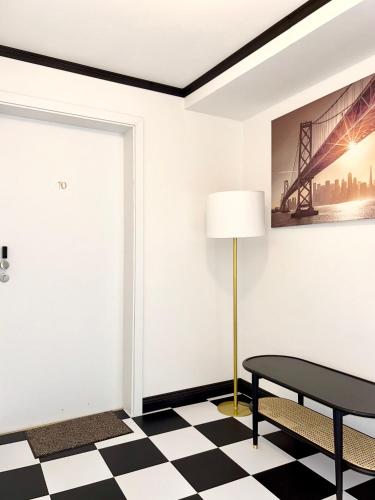 a black and white checkered floor with a table and a lamp at The Manhattan A Boutique Hotel By American Ease in Gravenwerth