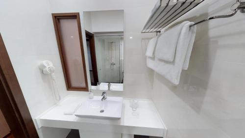 a white bathroom with a sink and a mirror at Luxury Skopje Apartments in Skopje