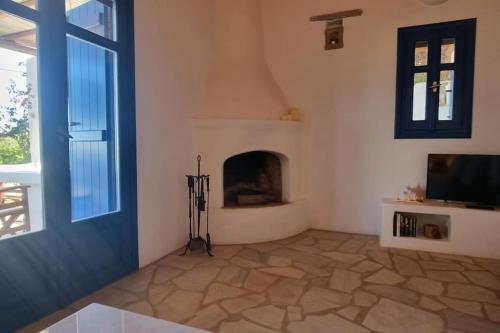 a living room with a fireplace and a blue door at Villa Kalliopi Ambelas Paros in Ambelas
