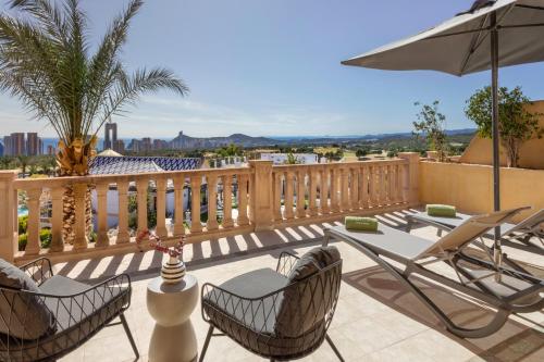 a patio with chairs and a table and an umbrella at Melia Villaitana in Benidorm