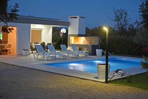 a swimming pool with chairs and a house at Holiday Home Maslina in Široki Brijeg