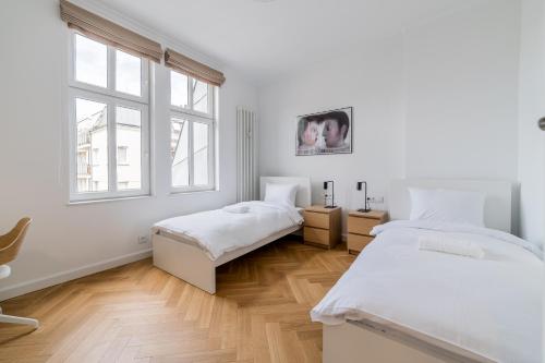 a white room with two beds and a window at Kochanowskiego Luxury Apartment by BookingHost in Poznań