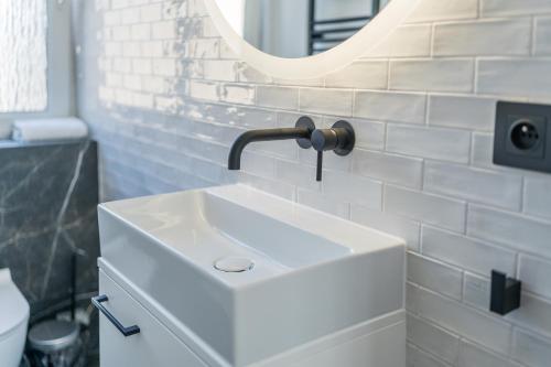 a bathroom with a white sink and a mirror at Kochanowskiego Luxury Apartment by BookingHost in Poznań