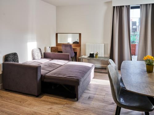 een slaapkamer met een bed, een tafel en stoelen bij Hampton Suites Serviced Apartments in Kingston upon Thames