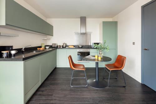 a kitchen with orange chairs and a table in it at Marlin Canary Wharf in London