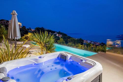 a jacuzzi tub on a patio with a pool at Green Tree Villas in Rabac