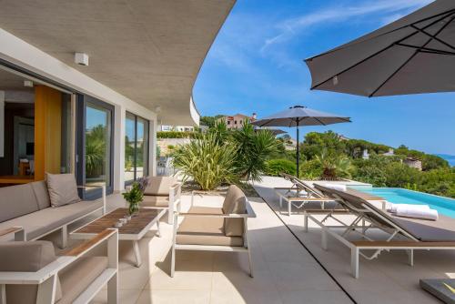 an outdoor patio with lounge chairs and an umbrella at Green Tree Villas in Rabac
