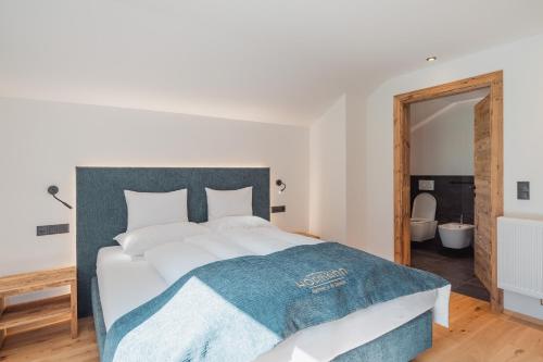 a bedroom with a large bed with a blue blanket on it at Apartments Hofmann in Prateria