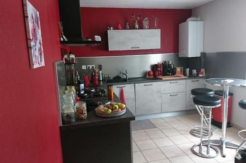 - une cuisine rouge avec un bol de fruits sur un comptoir dans l'établissement Maison Poitiers 3 chambres à 15 min Futuroscope, à Poitiers
