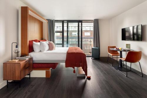a hotel room with a bed and a desk and a chair at Marlin Canary Wharf in London