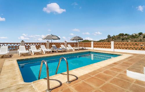 a swimming pool with chairs and umbrellas on a patio at Lovely Home In Torrox in Torrox