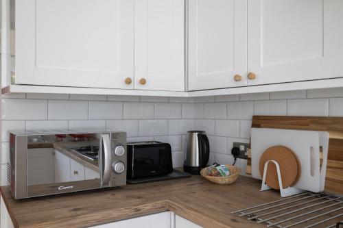 a kitchen with white cabinets and a microwave on a counter at Typical English Terraced House in Brighton & Hove