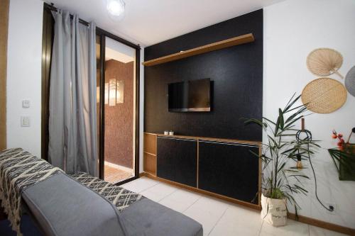 a living room with a couch and a tv on a wall at OZPED Flats Particulares Edifício Life Resort in Brasilia