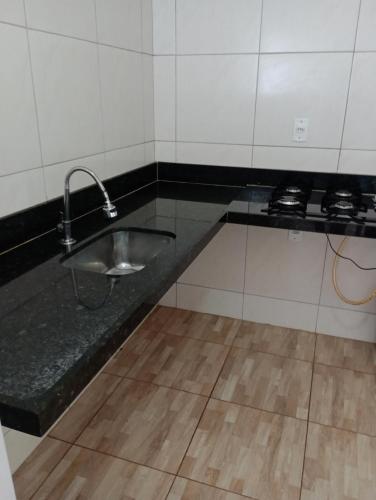 a kitchen with a sink in a black counter at Mariana Chale in São Miguel do Gostoso