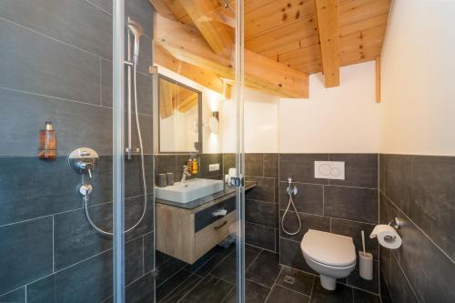 a bathroom with a shower and a toilet and a sink at 24 by AvenidA - Mountain Hotel in Kaprun
