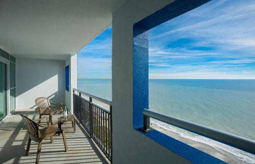 a balcony with two chairs and a view of the ocean at Bay View Resort Myrtle Beach in Myrtle Beach