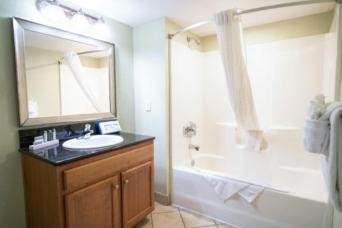 a bathroom with a sink and a tub and a mirror at Bay View Resort Myrtle Beach in Myrtle Beach