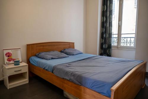 une chambre avec un lit avec une tête de lit en bois et une fenêtre dans l'établissement GuestReady - Tranquil City Haven in the Heart Nice, à Nice