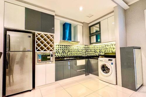 a kitchen with a refrigerator and a washer and dryer at Sophisticated 2BR Surabaya Apartment at Via Tower Ciputra World by Le Ciel Hospitality in Surabaya