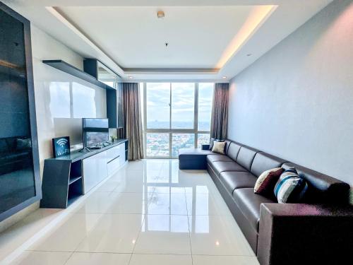 a living room with a couch and a large window at Sophisticated 2BR Surabaya Apartment at Via Tower Ciputra World by Le Ciel Hospitality in Surabaya