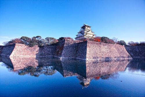 a stone bridge with a tower in the water at Hotel Keihan Tenmabashi in Osaka