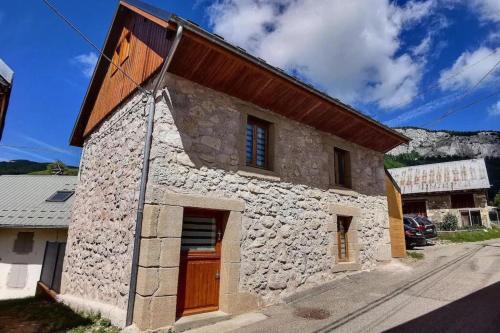 une maison en pierre avec une porte en bois dans une rue dans l'établissement Charmante maison au désert d'Entremont, à Les Déserts