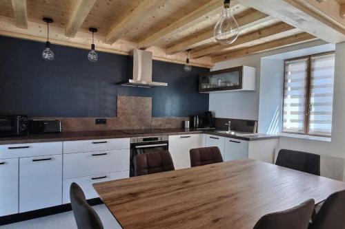 une cuisine avec des armoires blanches et une table en bois dans l'établissement Charmante maison au désert d'Entremont, à Les Déserts