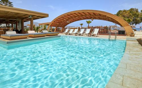 a large swimming pool with lounge chairs in a resort at Enorme Teatro Beach in Amoudara Herakliou
