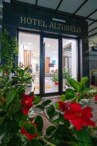 a hotel entrance with red flowers in front of a building at Altobelo Hotel in Vlorë