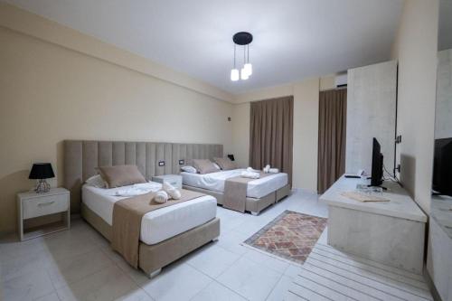 a large room with two beds and a television at Altobelo Hotel in Vlorë