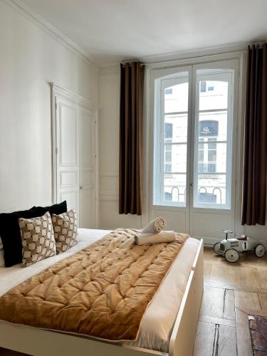 une chambre avec un grand lit avec une grande fenêtre dans l'établissement Le Duguesclin, hyper centre de Rennes, à Rennes