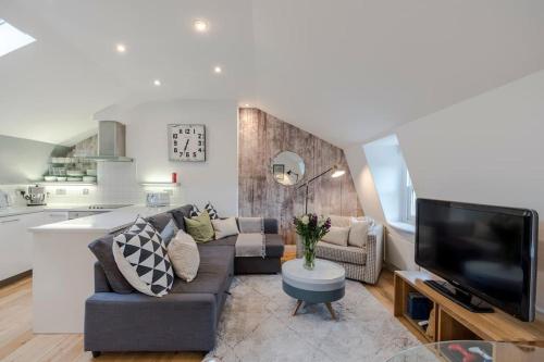 a living room with a couch and a tv at Kings Cross Two Bedroom Penthouse in London