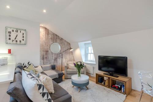 a living room with a couch and a flat screen tv at Kings Cross Two Bedroom Penthouse in London