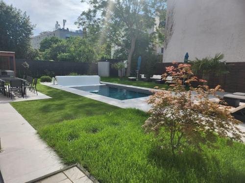 une cour avec une piscine et de l'herbe verte dans l'établissement Muka House, à Herblay