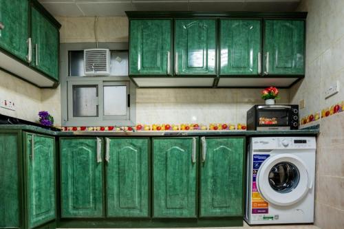 a green kitchen with a washing machine in it at Peaceful Room for Family or Couples in Abu Dhabi