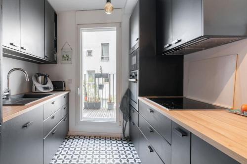une cuisine avec un sol carrelé noir et blanc et une fenêtre dans l'établissement Appartement incroyable en région parisienne, à Boulogne-Billancourt
