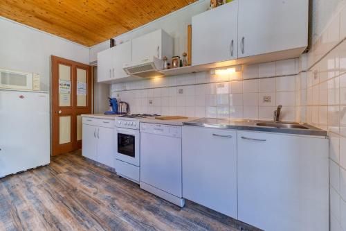 une cuisine avec des appareils blancs et un parquet dans l'établissement Maison de Village à St Pierre d'Entremont, à Saint-Pierre-dʼEntremont