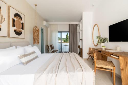 a bedroom with a bed and a desk with a television at Aspronissos Hotel in Skiathos